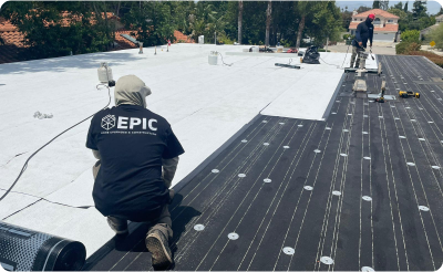 Workers from Epic Roof Replacement installing a new roof in San Leandro, with materials and tools on a flat rooftop.